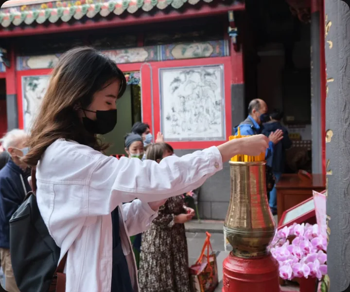 一名旅人在廟宇的油香爐前抽取籤枝