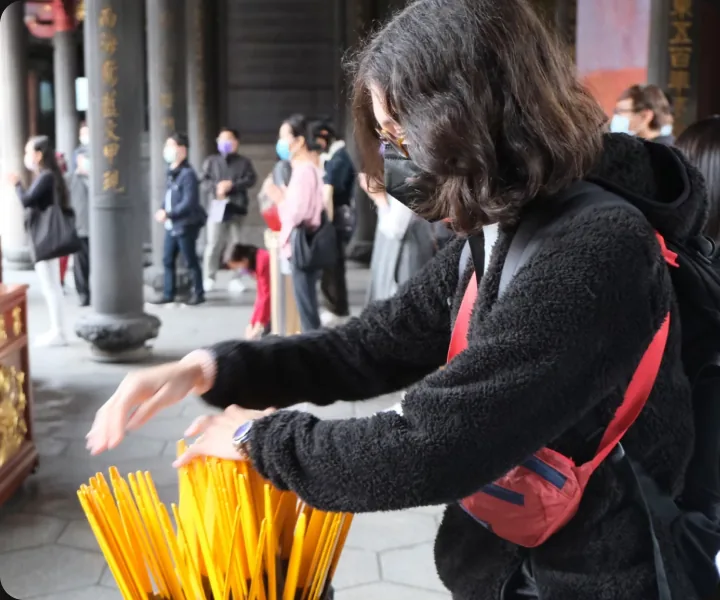 一名旅人在廟宇的籤筒前抽取籤枝